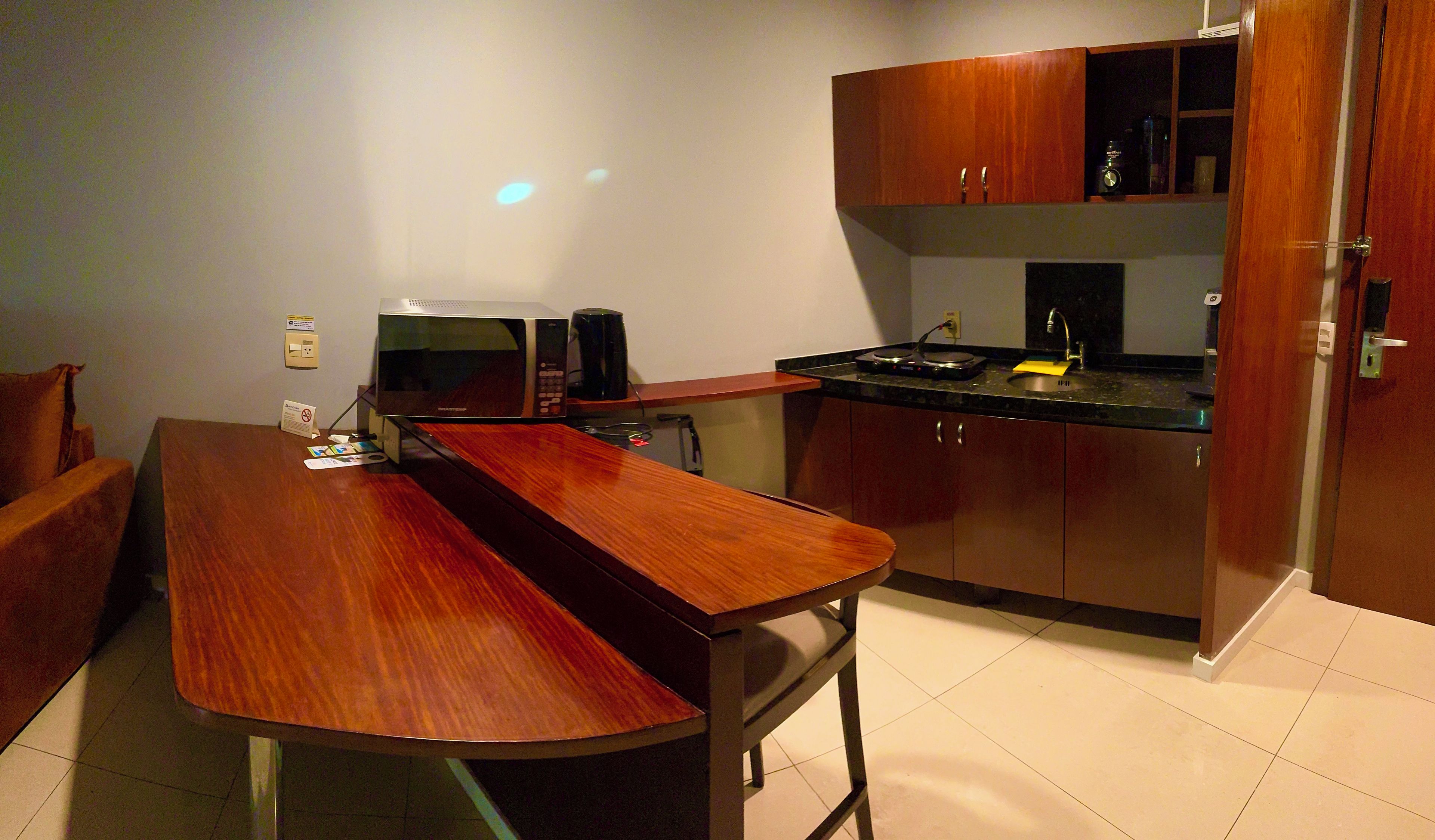 A compact kitchen with a microwave, coffee maker, and a sink.