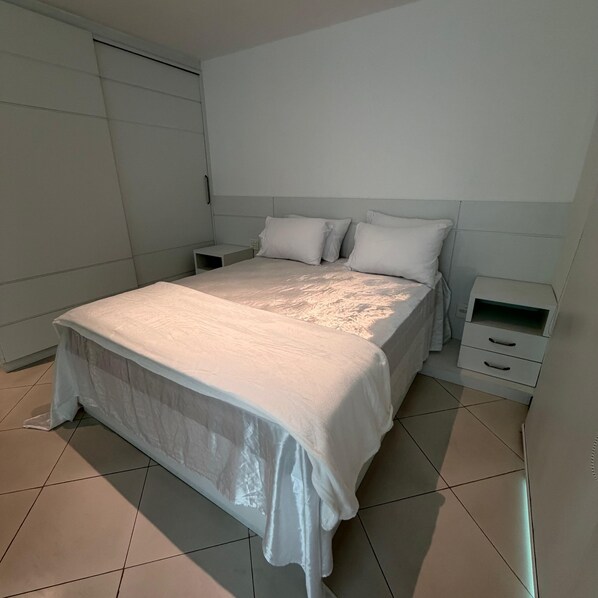 A bedroom with a bed, two bedside tables, and a wardrobe.