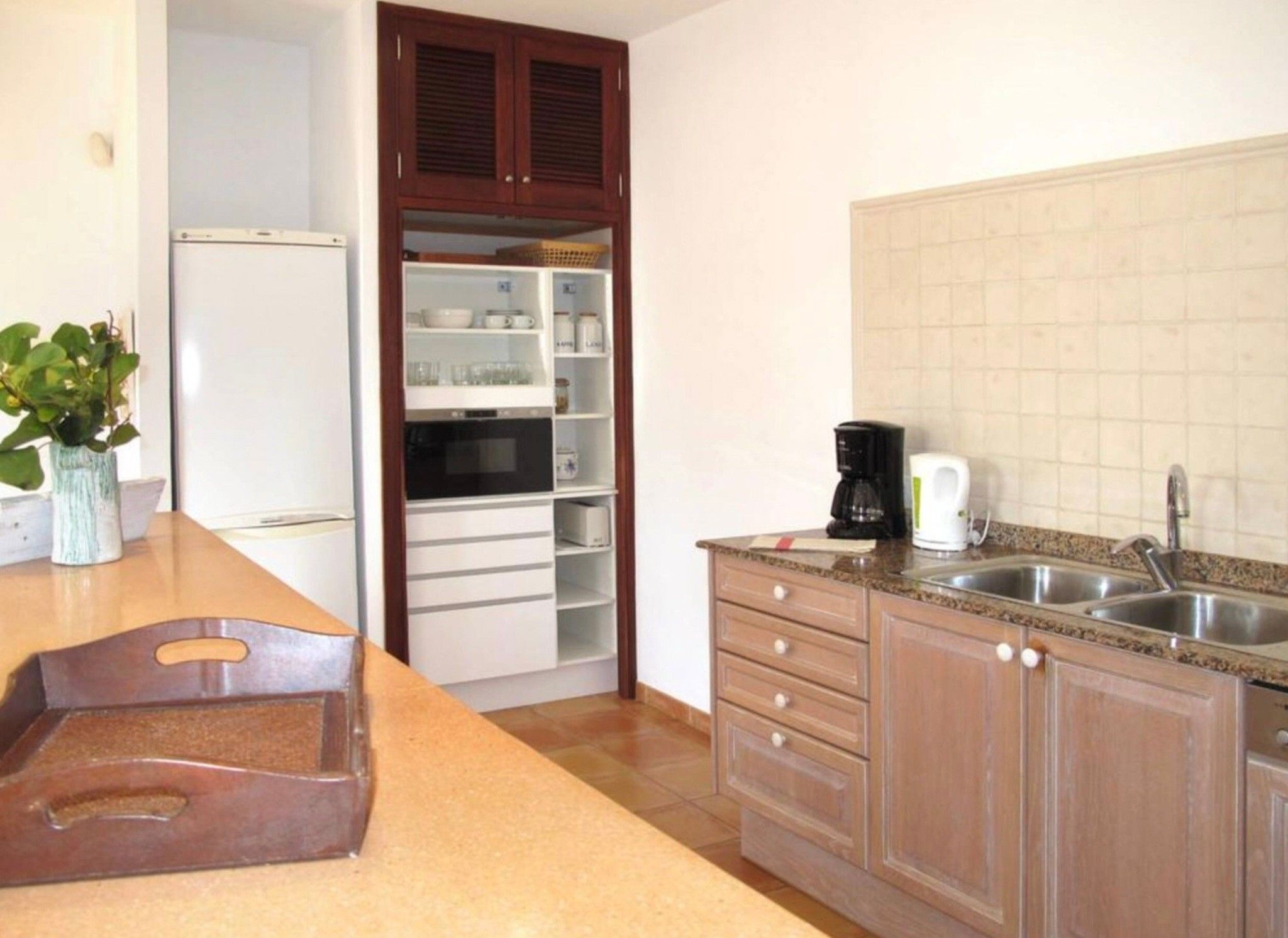 Eine Küche mit Kühlschrank, Mikrowelle, Backofen und Kaffeemaschine.