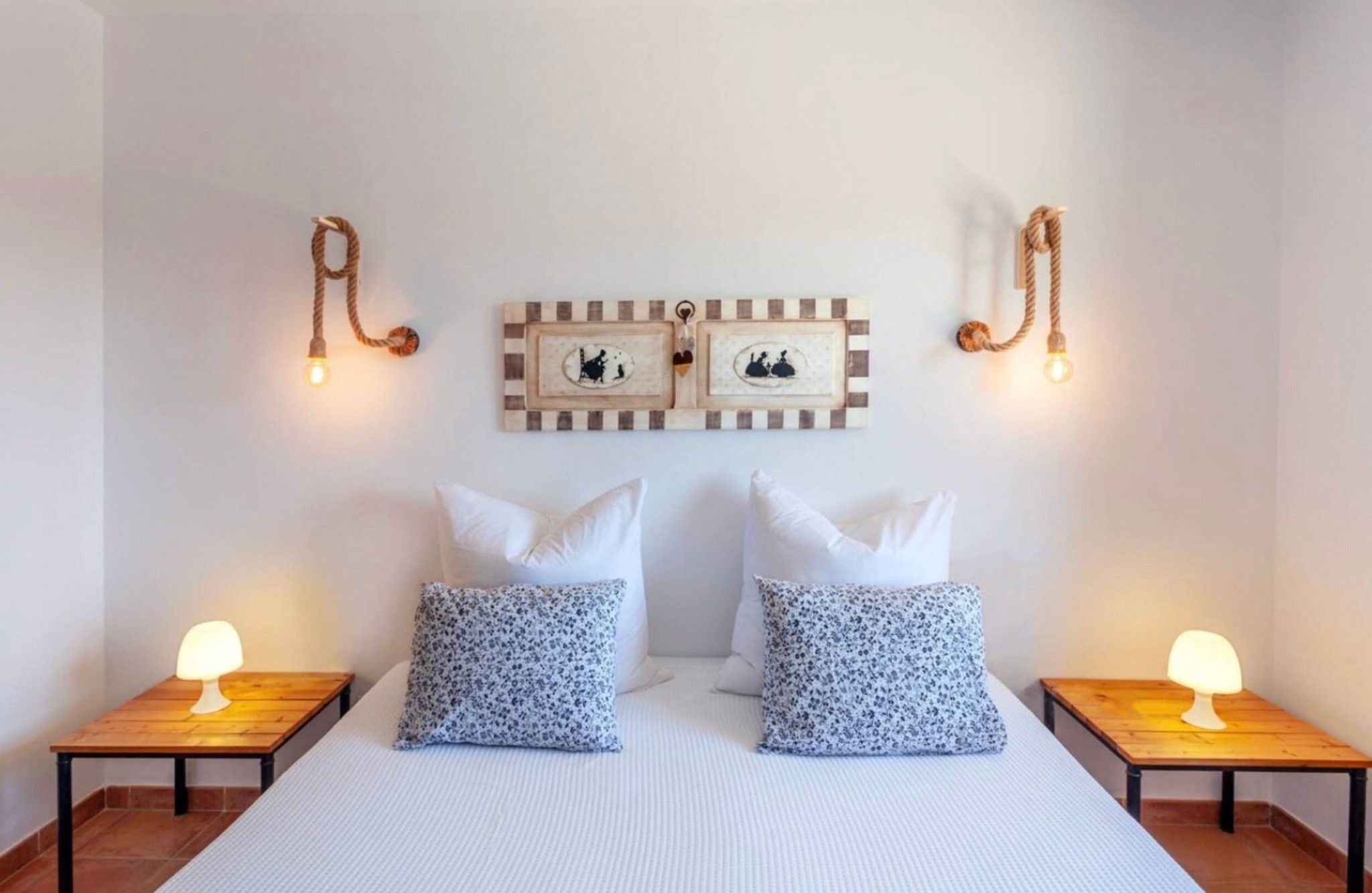 A hotel room with a bed, two nightstands, two wall-mounted lamps, and two framed pictures on the wall.