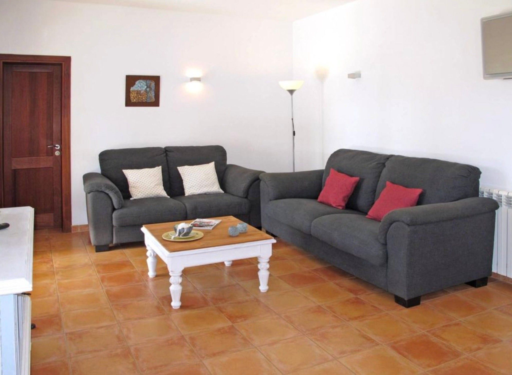 A living room with two grey sofas, a white coffee table, and a wooden door.