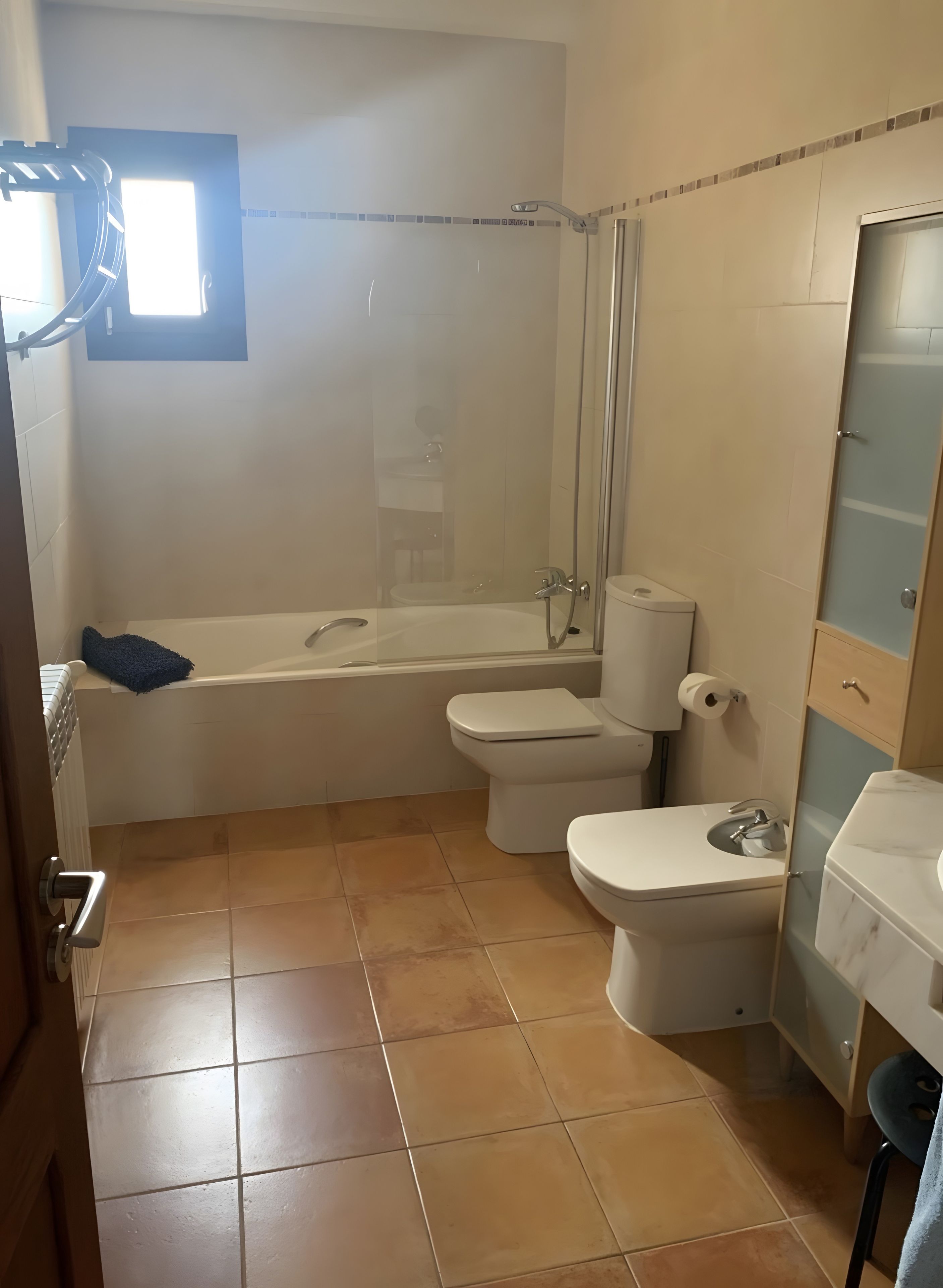 Une salle de bain avec une baignoire, deux toilettes, une douche et une fenêtre.