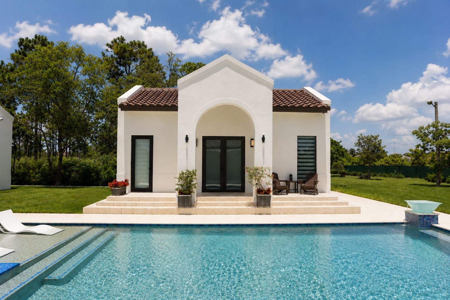 Une maison moderne avec une piscine, une terrasse dotée de chaises et une porte avec une fenêtre.