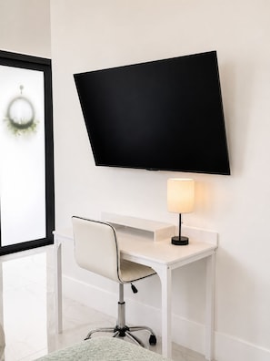 Un espace de bureau moderne avec un bureau blanc, un écran noir et une lampe.