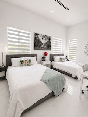 Une chambre à coucher moderne avec un grand lit, deux tables de chevet, un bureau et une lampe fixée au mur.