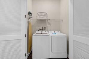 A laundry room with two white front-loading washing machines and a white drying rack.
