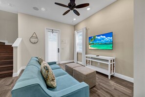 A living room with a blue sofa, a television, and a ceiling fan.