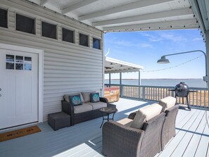 A covered deck with outdoor furniture, a barbecue grill, and a view of the water. - Private lakefront home with boat ramp! (Runaway Bay)
