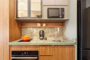A compact kitchen with a microwave, coffee maker, and a sink. - Privilege Jardins - Elegance with parking included (São Paulo)