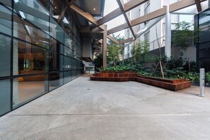 A modern building with large glass windows, a central courtyard with seating, and a metal framework structure. - Privilege Jardins - Elegance with parking included (São Paulo)
