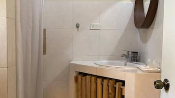 Un baño con cortina de ducha, un lavamanos, un espejo y un perchero para toallas.