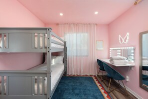 Une chambre avec des lits superposés, un coin coiffeuse, un miroir avec éclairage et une décoration en forme de papillon sur le mur.