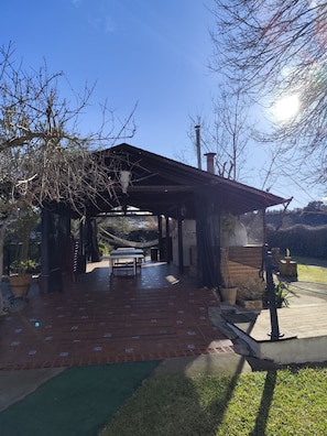 Un patio al aire libre con una mesa, sillas, una hamaca y una zona de estar cubierta.