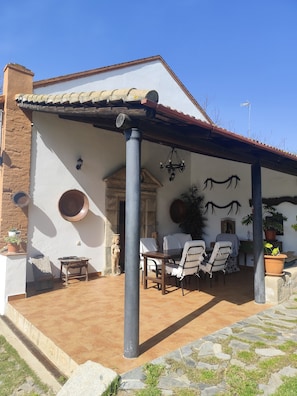Un espacio de patio cubierto con mesa y sillas, una estatua y una planta en maceta.