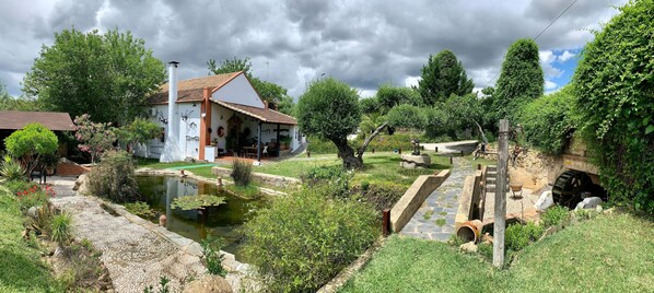 A traditional house with a garden, a pond, and a water wheel.