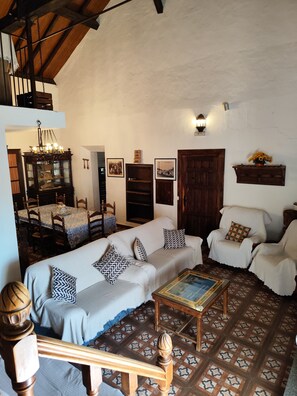 Una sala de estar acogedora con un sofá, sillones, una mesa de centro y un comedor con mesa y sillas.
