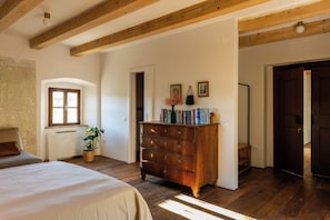 Quarto com cômoda de madeira, uma cama, radiador e janela.