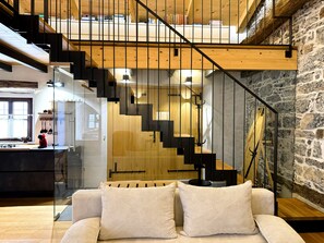 Un interior moderno con una escalera, una zona de cocina y un espacio de descanso con cojines.