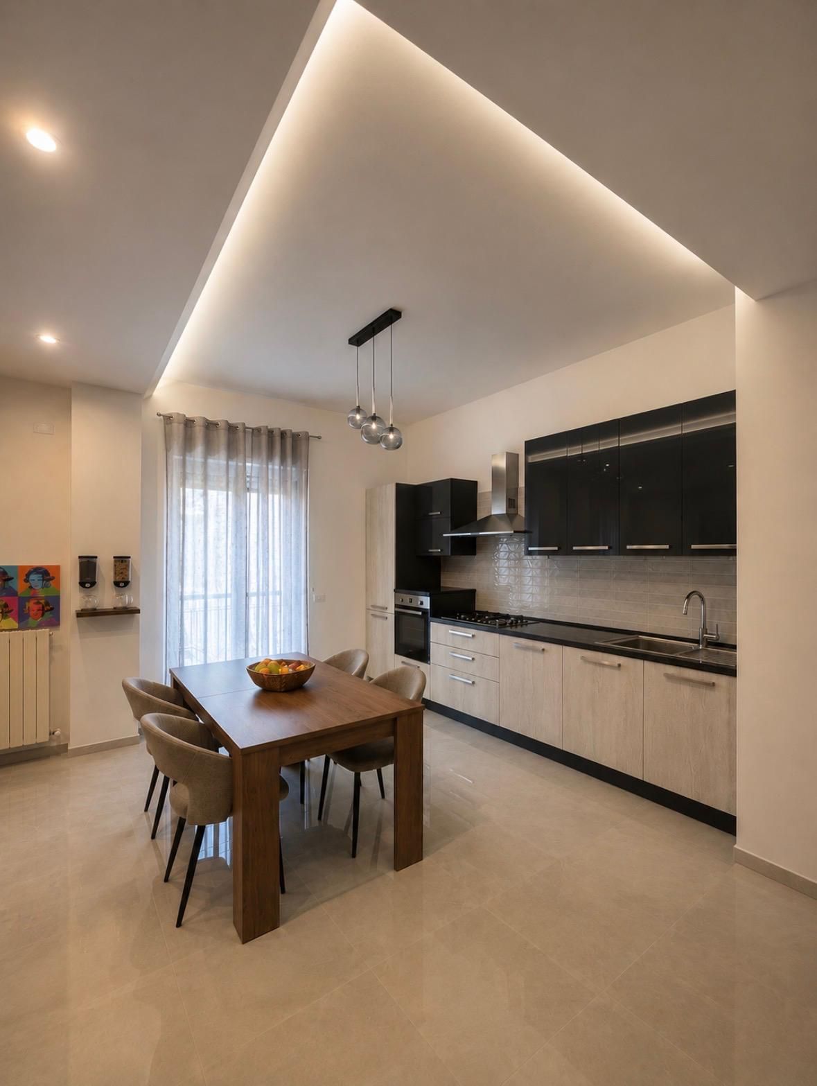 A modern kitchen with a dining area, featuring a wooden table, chairs, and a bowl of fruit.