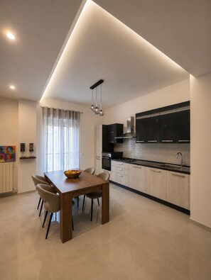Una cocina moderna con comedor, que incluye una mesa de madera, sillas y un tazón de fruta.