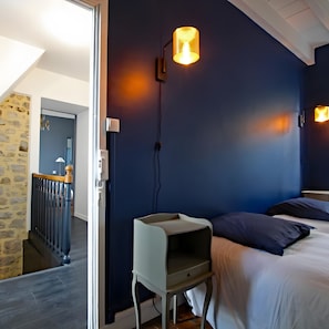 A bedroom with a bed, a nightstand, a lamp, and a wall-mounted light fixture. - Cottage 'Gite Le Sainte Marie' with Private Terrace, Private Garden and Wi-Fi (Sainte-Marie-du-Mont)