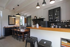 A kitchen with a wooden island, black cabinets, and pendant lighting. - Cottage 'Gite Le Sainte Marie' with Private Terrace, Private Garden and Wi-Fi (Sainte-Marie-du-Mont)