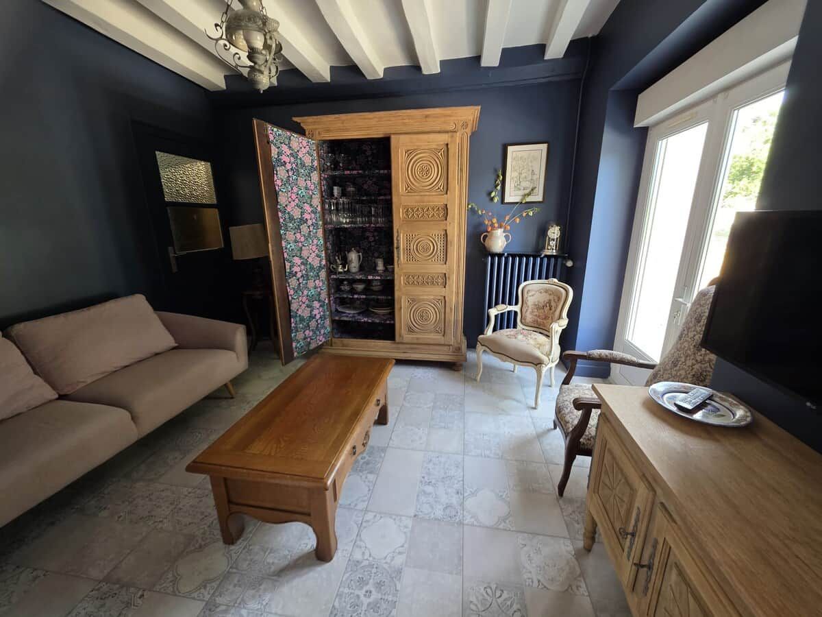 Una sala de estar con sofá, mesa de centro, mueble para televisión y aparador con adornos.