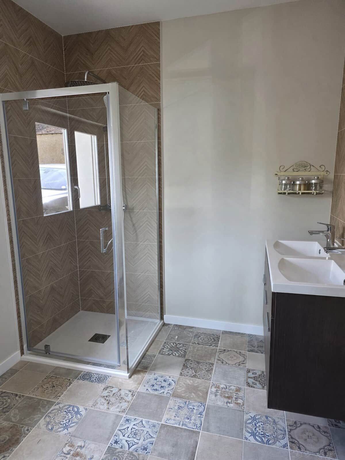 A bathroom with a shower, a sink, and patterned tiles.