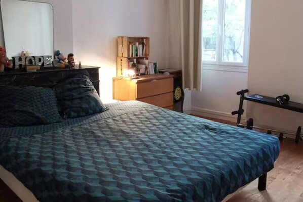 A bedroom with a bed, dresser, and a window.