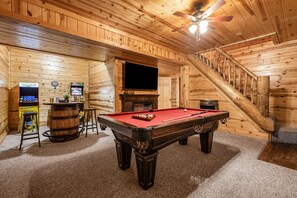 A wooden interior with a pool table, a television, and arcade games. - Abode at Big Pine – Formerly Western Hideaway (Logan)