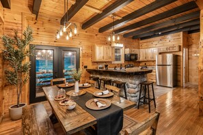 A wooden interior with a dining area, kitchen, and a stone island. - Abode at Big Pine – Formerly Western Hideaway (Logan)