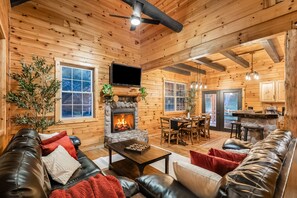 A cozy cabin interior with a fireplace, leather furniture, and a dining area. - Abode at Big Pine – Formerly Western Hideaway (Logan)