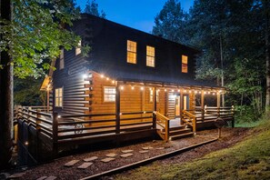 A log cabin with a porch, wooden steps, and string lights. - Abode at Big Pine – Formerly Western Hideaway (Logan)