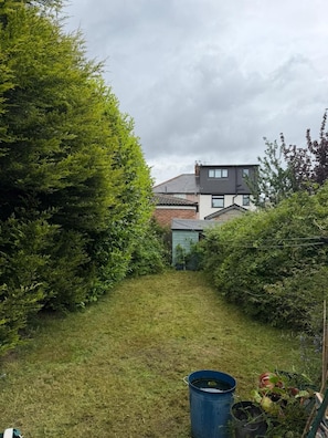 Ein grasbewachsener Pfad führt zu einem Haus mit einem geneigten Dach und einem sichtbaren Schornstein.