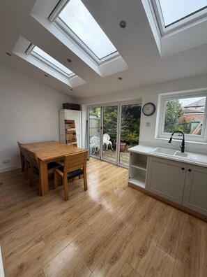 Eine Küche mit Dachfenstern, einem Esstisch und Blick ins Freie.