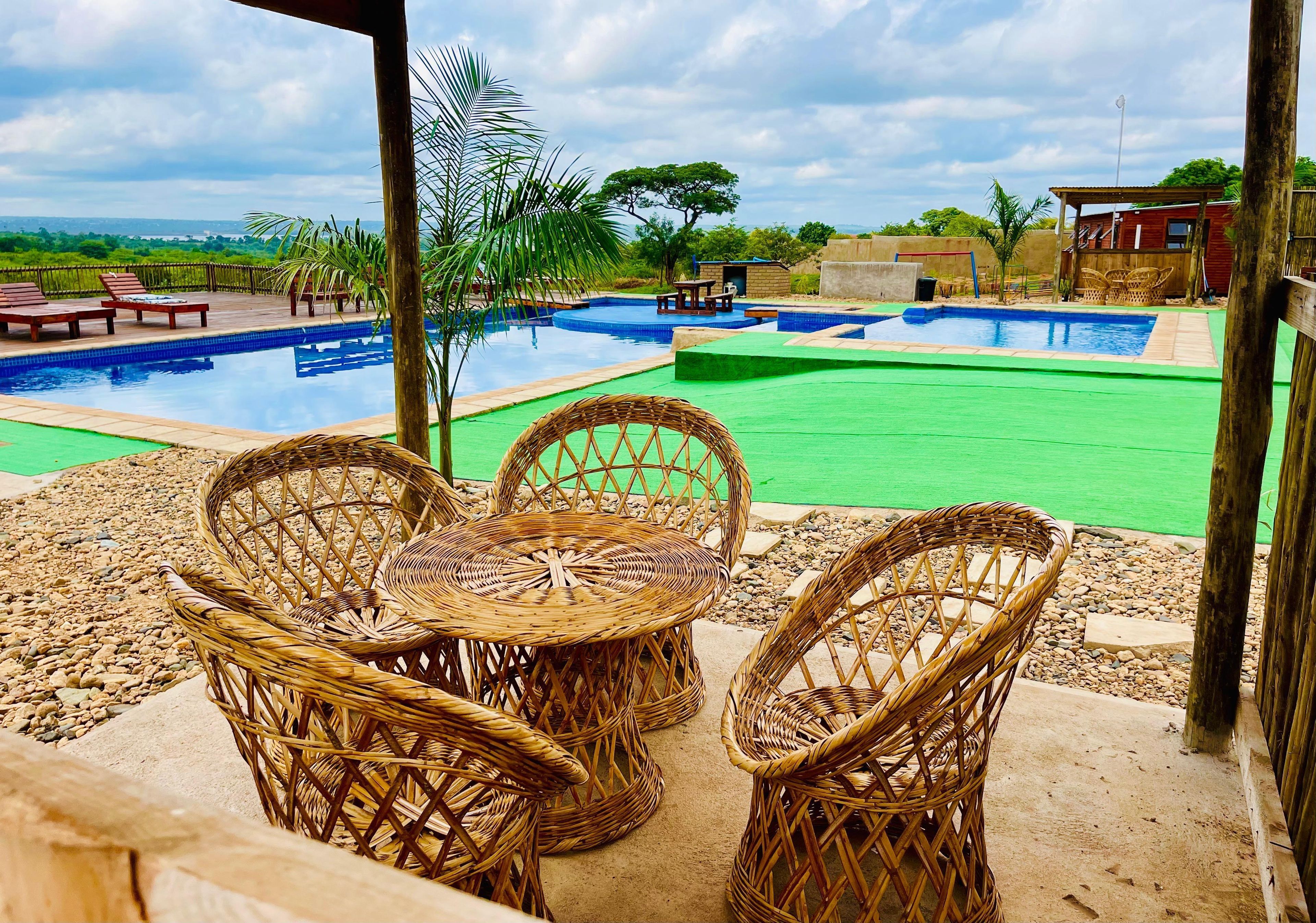 A pool area with wicker furniture and a view of the landscape.