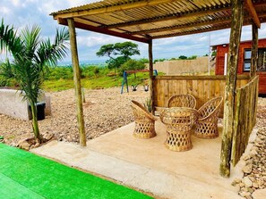 A covered outdoor seating area with wicker chairs and a wooden structure.