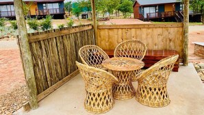 Un espace extérieur aménagé, abrité et doté de mobilier en osier, d’une table en bois et offrant une vue sur les environs.