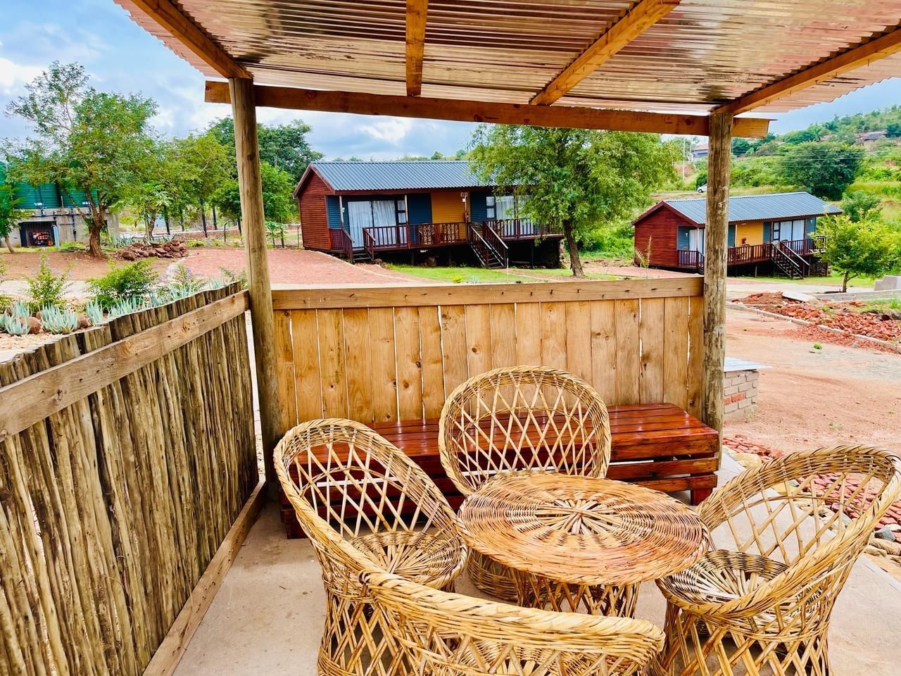 Un espacio de estar techado al aire libre con mobiliario de mimbre y una mesa de madera.