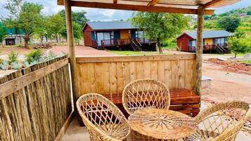 Un espacio de estar techado al aire libre con mobiliario de mimbre y una mesa de madera.