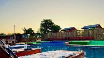 A pool area with multiple swimming pools, lounge chairs, and a wooden deck.