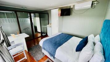 Una habitación de hotel moderna con cama, escritorio y televisor.