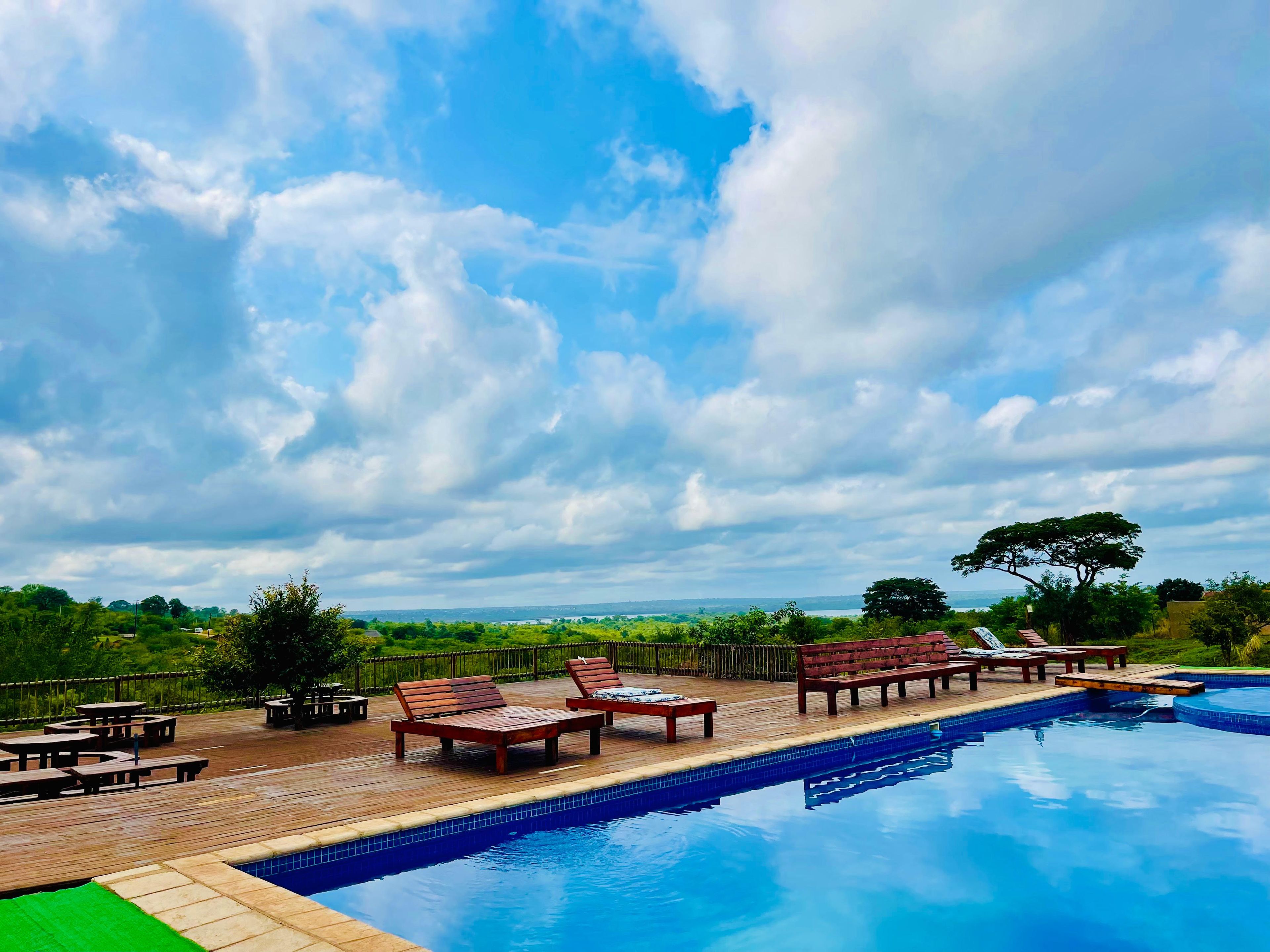 A pool area with lounge chairs and a wooden deck.