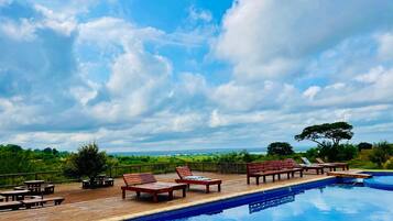 A pool area with lounge chairs and a wooden deck.