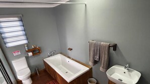 Un baño con una bañera de madera, un lavabo blanco y un inodoro.