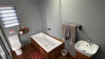 Ein Badezimmer mit einer Holzwanne, einem weißen Waschbecken und einer Toilette.
