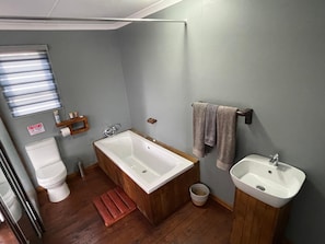A bathroom with a wooden bathtub, a white sink, and a toilet. - Damview Eco Lodge  (Thohoyandou)