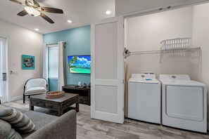 A laundry room with two front-loading washers and dryers, a ceiling fan, and a television on the wall. - Sun Shack Cottage | Private Pool Near Disney & Island H2O Access - 8096KD (Kissimmee)
