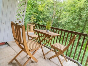 A wooden deck with a table and chairs, surrounded by a white fence and lush greenery. - "seenelke" (St. Peter-Ording)
