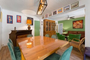 Zona pranzo con tavolo e sedie in legno, un armadio e una parete verde con quadri.